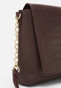 Hnědá kabelka z umělé kůže s texturou krokodýlí kůže, zlatým řetízkovým kováním a elegantním obdélníkovým tvarem s klopou na zavírání.