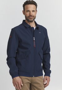 Navy blue jacket with a zip front, stand collar, and two front pockets. Features a red and white accent on the left chest and zippered arm pocket.