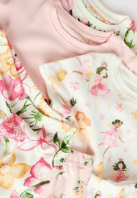 Trzy bawełnowe T-shirty w kolorze różowym i białym, ozdobione kwiatowymi wzorami i ilustracjami wróżek. Teksturowana tkanina z szytymi brzegami i okrągłymi dekoltami.