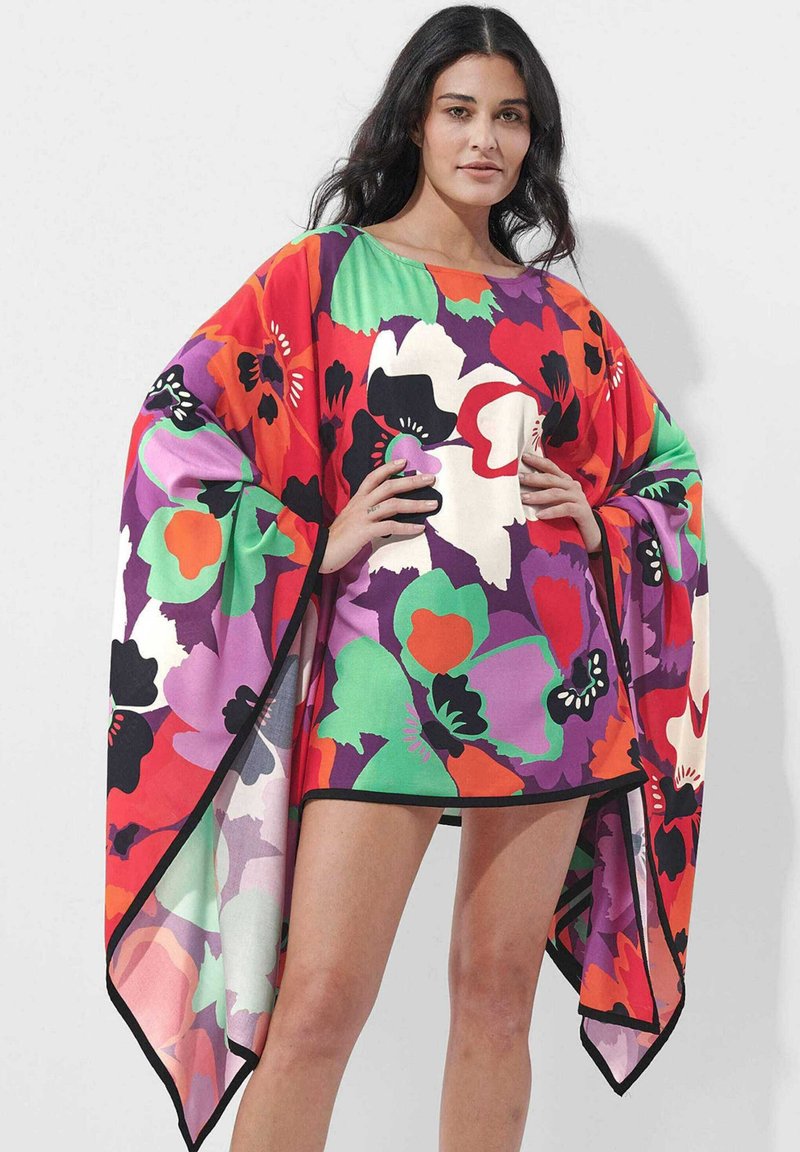 Floral poncho in vibrant red, purple, and green with black accents. Lightweight fabric, oversized shape, and wide sleeves for flowy movement.