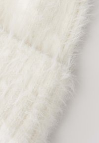 Cream-colored knit fabric with fluffy, soft fibers creating a textured, cozy appearance.