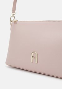 Borsa in pelle sintetica rosa con una texture liscia, caratterizzata da un logo metallico dorato e una tracolla rimovibile.