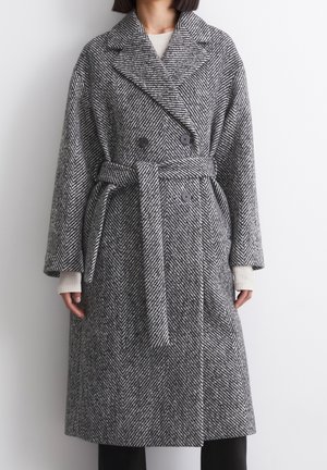 Wool-blend herringbone coat in black and white, featuring a double-breasted front, wide collar, and a belted waist.