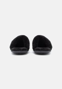 Papuci negri pufoși cu un design cu spatele deschis, textură moale, talpă de cauciuc plată și branț căptușit pentru confort.