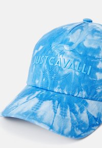 Blå tie-dye caps laget av kordfløyel med en teksturert overflate. Har en hevet "JUST CAVALLI"-logo og en buet skygge.