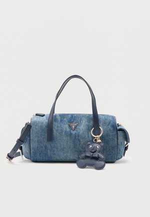 Sac à main en jean avec des anses bleu marine, une bandoulière détachable et un porte-clés ourson bleu marine suspendu à l'une des anses.