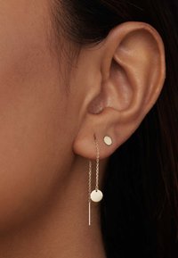 Boucles d'oreilles en or avec un petit clou circulaire et un design en goutte avec une chaîne, se terminant par un disque rond et un accent en barre verticale.