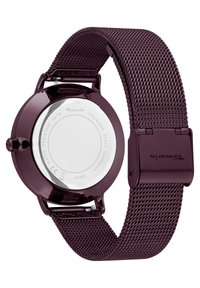 Montre en métal maillé bourgogne avec un boîtier rond, un dos en acier inoxydable et un fermoir sécurisé. Résistante à l'eau jusqu'à 3 ATM.