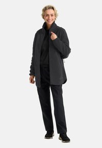 Fleecejacke in Dunkelgrau mit hohem Kragen, Frontreißverschluss und Seitentaschen, kombiniert mit schwarzen Hosen und Schuhen. Die Textur ist weich und flauschig.