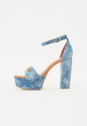 Sandali platform in denim con tacco chunky, dotati di cinturino regolabile alla caviglia e un accento in metallo dorato, che presentano una sfumatura di blu chiaro.