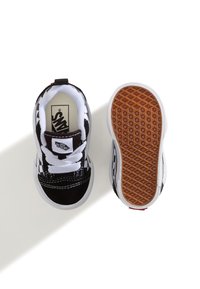 Mustat ja valkoiset ruudulliset kangaskengät, joissa on valkoiset nauhat, pehmustettu varsi ja kumipohja, jossa on kuvioitu pito. 