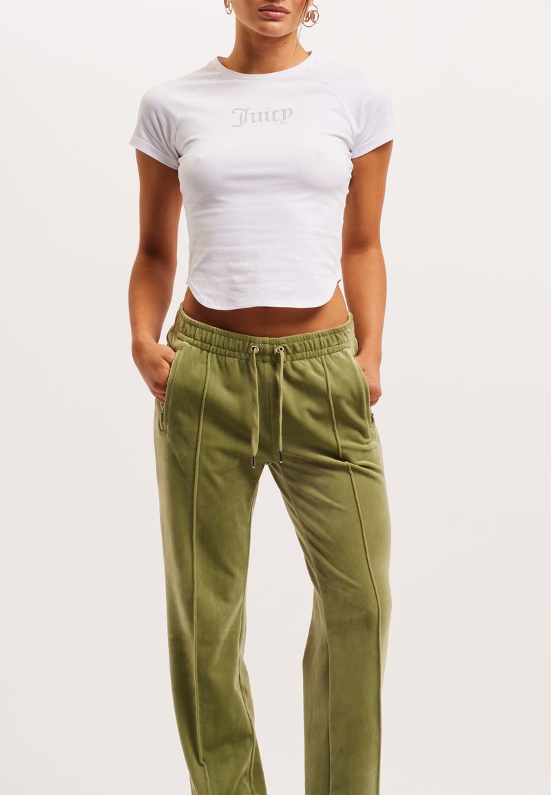 Valge lühike T-särk, millel on halli värvi "Juicy" tikand, koos oliivroheliste, pehmete, laia säärega joggeritega, millel on elastne vöökoht ja taskud.