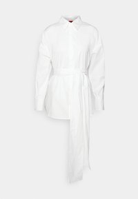 Robe-chemise blanche à manches longues avec col pointu, patte de boutonnage cachée et large ceinture en tissu nouée à la taille, tombant droit.