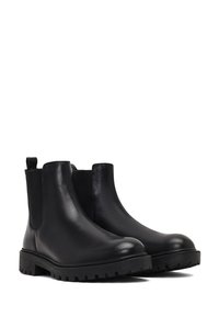 Bottines Chelsea en cuir noir avec panneaux élastiques sur les côtés, bout rond et semelle en caoutchouc texturée et robuste pour une meilleure adhérence. Tirant à l'arrière pour un enfilage facile.