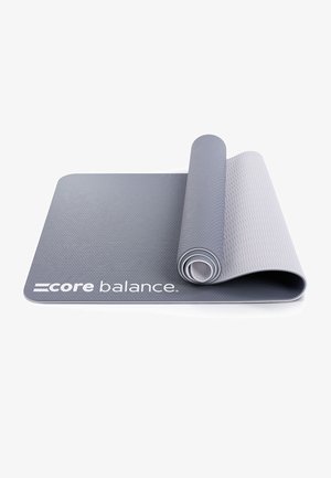 Gray exercise mat with a textured surface, rolled partially, featuring the brand "core balance" printed in white at the bottom edge.