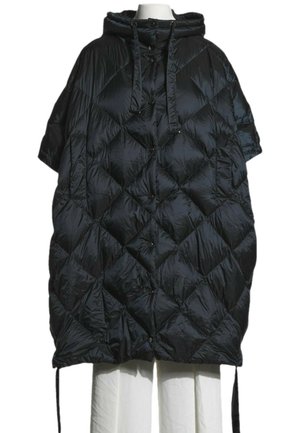 Czarna pikowana, oversize kurtka puchowa z kapturem, krótkimi rękawami i sznurkami, stylizowana na manekinie bez głowy, ubranym w białe spodnie.