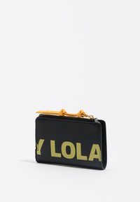 Cartera de cuero negra con un estampado amarillo de "LOLA", presenta un cierre de cremallera y un detalle amarillo en el tirador de la cremallera. Forma rectangular compacta.
