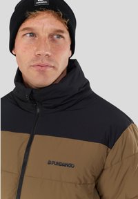 Black and brown insulated jacket with high collar, zipper closure, and embroidered logo on the chest. Soft texture and sporty design.