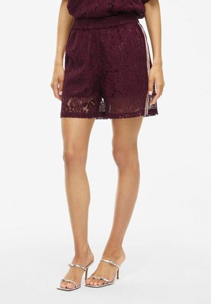 Burgunderfarvede blonde shorts med elastisk talje, prydet med et blomstermønster og gennemsigtig design. Sammen med sølvfarvede strophæle.