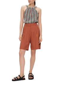 Gestreepte haltertop in meerdere kleuren, gecombineerd met hoge roestkleurige shorts. Schoeisel bestaat uit zwarte bandjesandalen. Glad stoftextuur.