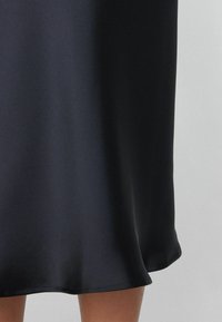 Schwarzes Satin-Kleid mit glatter Textur, A-Linien-Form und einem Saum, der sanft ausstellt. Hat ein schlichtes Design ohne Verzierungen.
