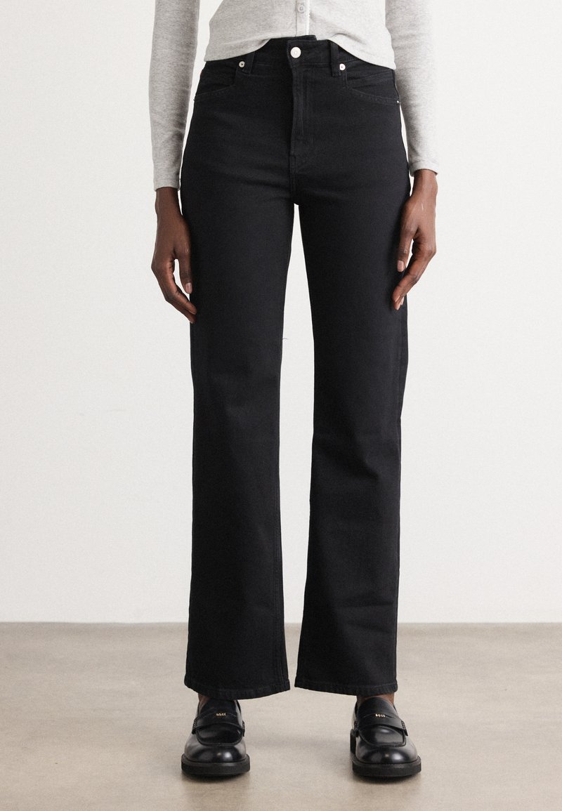 Sorte høytlivs jeans med rett ben-design, som har en ren silhuett og minimalt med metallspenne. Tøyet har en jevn tekstur.