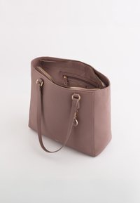 Stor mauve tote bag lavet af tekstureret materiale med to lange stropper, en lynlåslomme og hardware i guldtone.