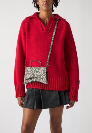 Pull en tricot rouge avec col, manches côtelées et jupe plissée à carreaux noirs. Petit sac à main imprimé léopard avec une poignée supérieure et une bandoulière.