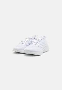 Baskets de sport blanches avec une tige en maille, semelle rembourrée et bout rond. Les lacets sont passés à travers des œillets renforcés. Design simple.