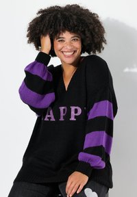 Maglione nero a maglia con strisce viola e la scritta "HAPPY" in lettere glitterate. Design a V, fit oversize, polsini e orlo a coste.