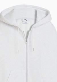 Ανοιχτό γκρι φούτερ με φερμουάρ ολόκληρο, κουκούλα με κορδόνι, μπροστινές τσέπες και διακριτικό  λογότυπο Puma στο στήθος.