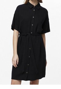 Abito nero a camicia con maniche corte, chiusura a bottoni sul fronte e cintura in vita. Realizzato in un tessuto testurizzato, presenta bottoni metallici e un colletto.