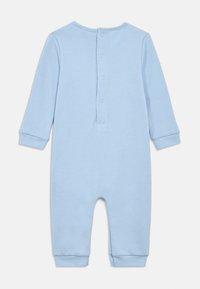 Vaalean sininen, pitkähihainen vauvan haalari, jossa on painonapit selän pitkin helpottamaan pukemista sekä resorit nilkoissa ja ranteissa.