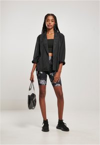 Musthave musta oversize bleiser, mille varrukad on üles keeratud, musta lühikese topi peal, koos lillemustriliste jalgrattašortidega ja mustade tennistega. Sellega kaasas selge kott.