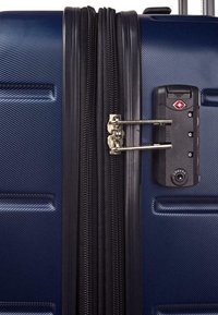 Maleta rígida de color navy con un acabado texturizado, que cuenta con una cremallera negra, un mecanismo de bloqueo metálico y un candado de combinación para mayor seguridad.