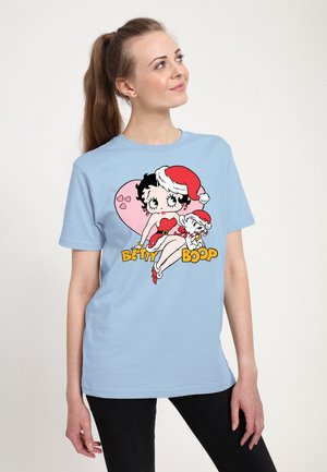 Svetle modré triko s krátkým rukávem s grafikou Betty Boop v červených šatech a vánoční čepici, s bílými akcenty a černým textem.