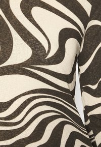 Leichtes Oberteil mit einem abstrakten Wellenmuster in Schwarz und Creme, strukturiertem Stoff und langem Ärmel-Design.