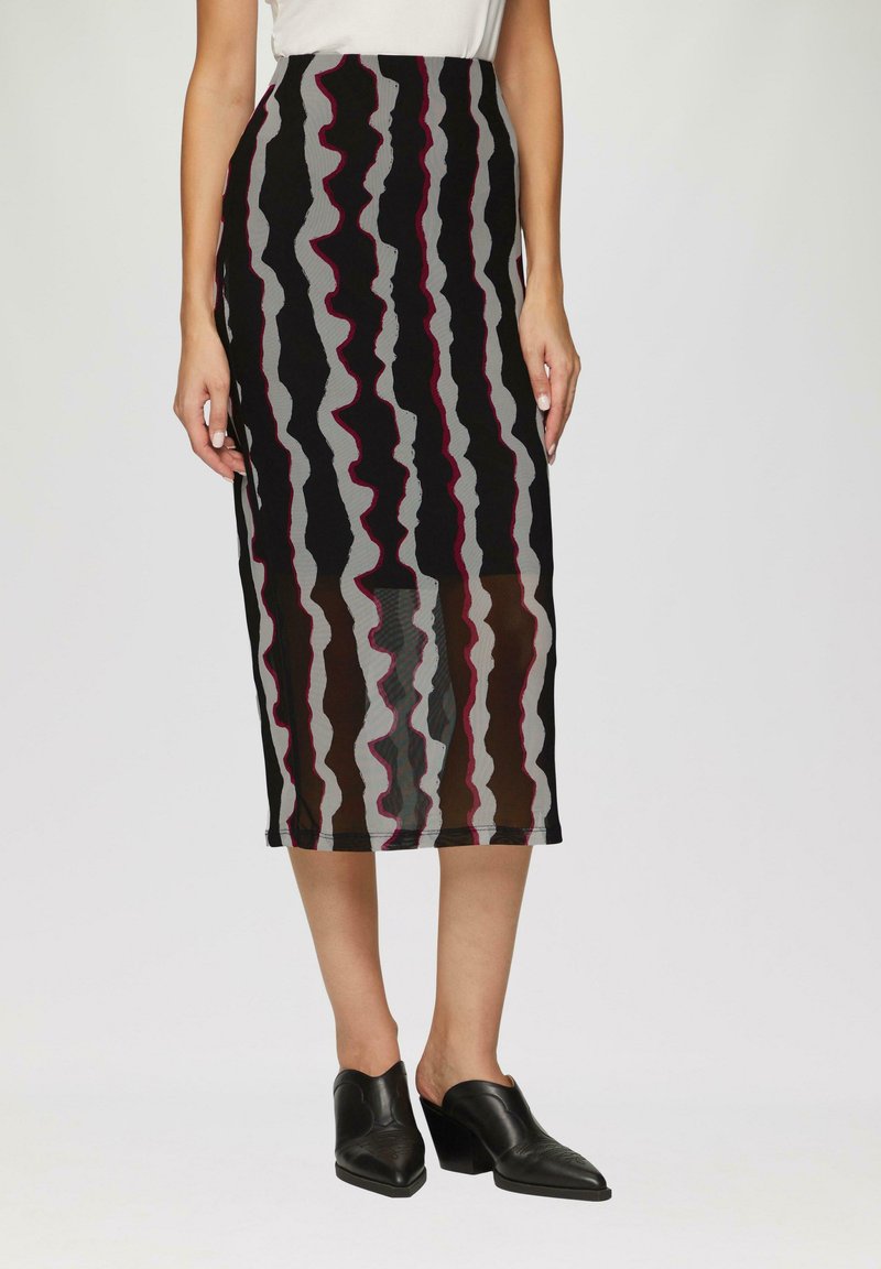 Jupe midi noire, grise et bordeaux avec des motifs ondulés, coupe ajustée et tissu doux et texturé. Associée à des mules noires à talons.