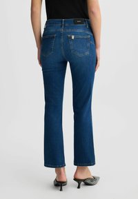 Jeans svasati blu scuro con vita media, cinque tasche, dettagli cuciti e accessori in tono dorato sulle tasche posteriori.