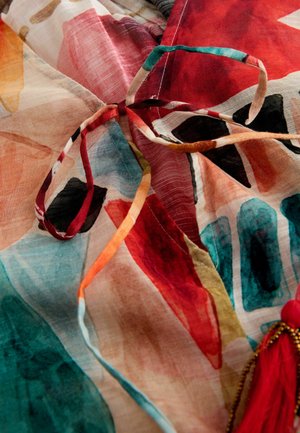 Daugiaprasmis, lengvas audinys su abstrakčiais gėlių raštais. Yra surišta juostelė ir raudonas kutas. Tekstūruota, pusiau permatoma medžiaga.