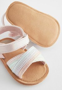 Ružová textilná sandála s prekrývajúcimi sa popruhmi v pastelových odtieňoch, so softsuede podošvou, nastaviteľným remienkom na členku a zaobleným tvarom.