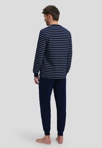 Camiseta de rayas azul marino y blanca de manga larga combinada con pantalones jogger azul marino lisos, con puños elásticos y un ajuste relajado.