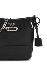 Bolso de mano de cuero negro con acabado texturizado, herrajes plateados, correa de cadena y una etiqueta de logo desmontable. Diseño elegante con forma estructurada.