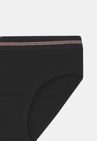 Sous-vêtements noirs avec une texture côtelée, dotés d'une taille étroite avec une bande métallique rose sur le haut.