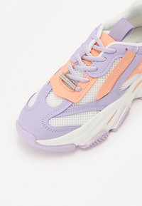 Baskets atlantiques violettes et oranges avec des panneaux en mesh, semelle en caoutchouc, fermeture à lacets et détail de logo. Embout rond avec des accents texturés.