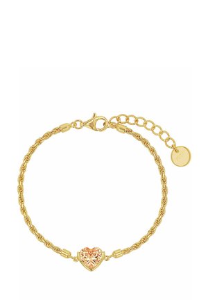 Pulsera de cadena dorada con una piedra central de forma de corazón color durazno y un cierre ajustable con una pequeña etiqueta redonda.