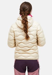 Beige dynejakke med quiltet design, der har en hætte og en kontrasterende lyserød krave. Glat tekstur med en figursyet silhuet.