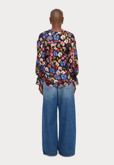 Blusa nera a fiori con vivaci fiori multicolori, maniche lunghe e vestibilità ampia abbinata a jeans in denim blu a gamba larga.