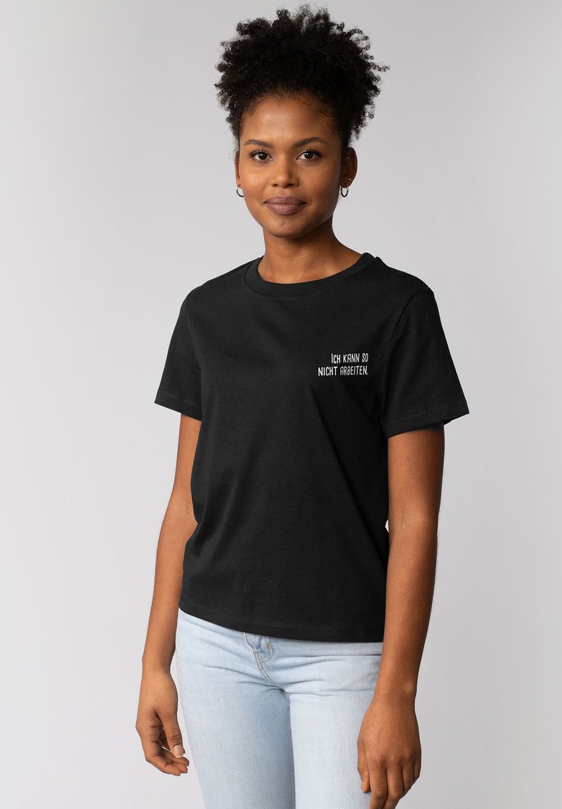 Schwarzes Baumwoll-T-Shirt mit kurzen Ärmeln. Mit weißem Text "ICH KANN SO NICHT ARBEITEN" auf der linken Seite. Lässiger Schnitt.