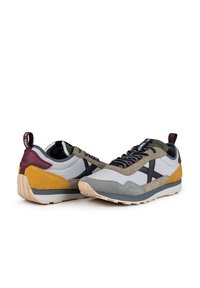 Zapatillas deportivas que combinan ante y tela en tonos grises, amarillos y burdeos. Diseñadas con detalles en negro y suela exterior de goma texturizada.